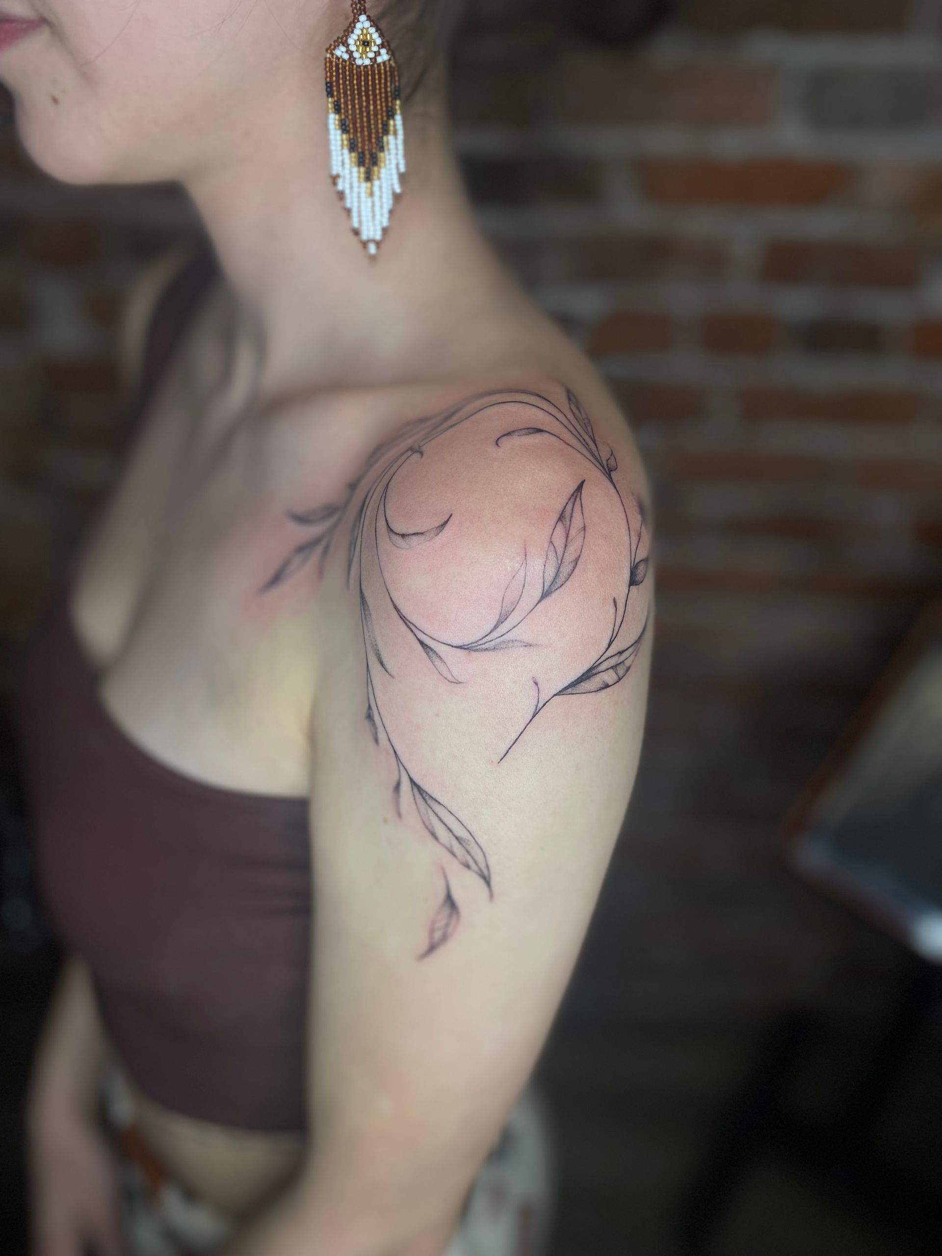 A woman with a tattoo on her shoulder and earrings.