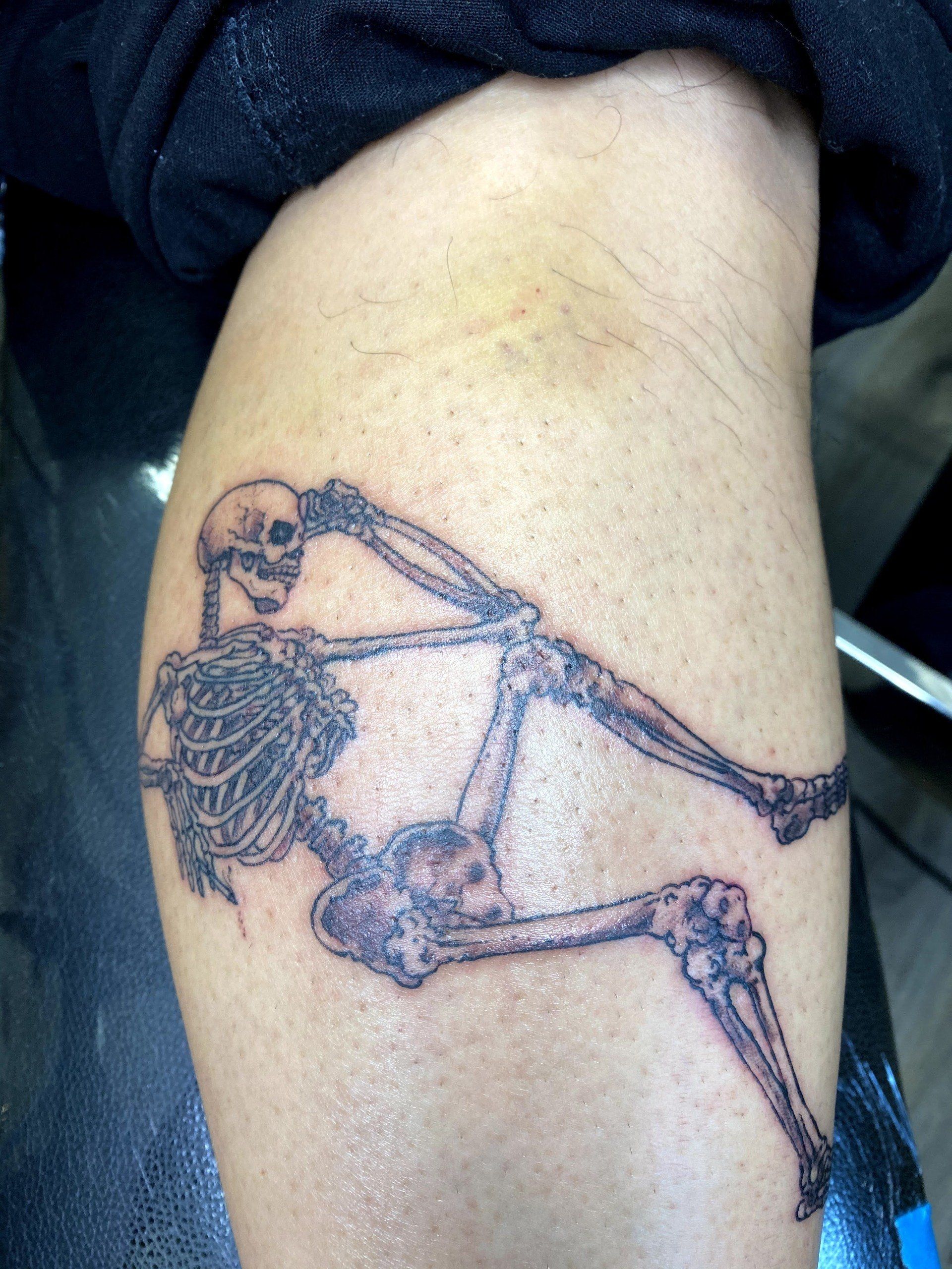 A person has a tattoo of a skeleton on their leg