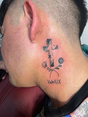 A man has a tattoo of a cross and flowers on his neck.