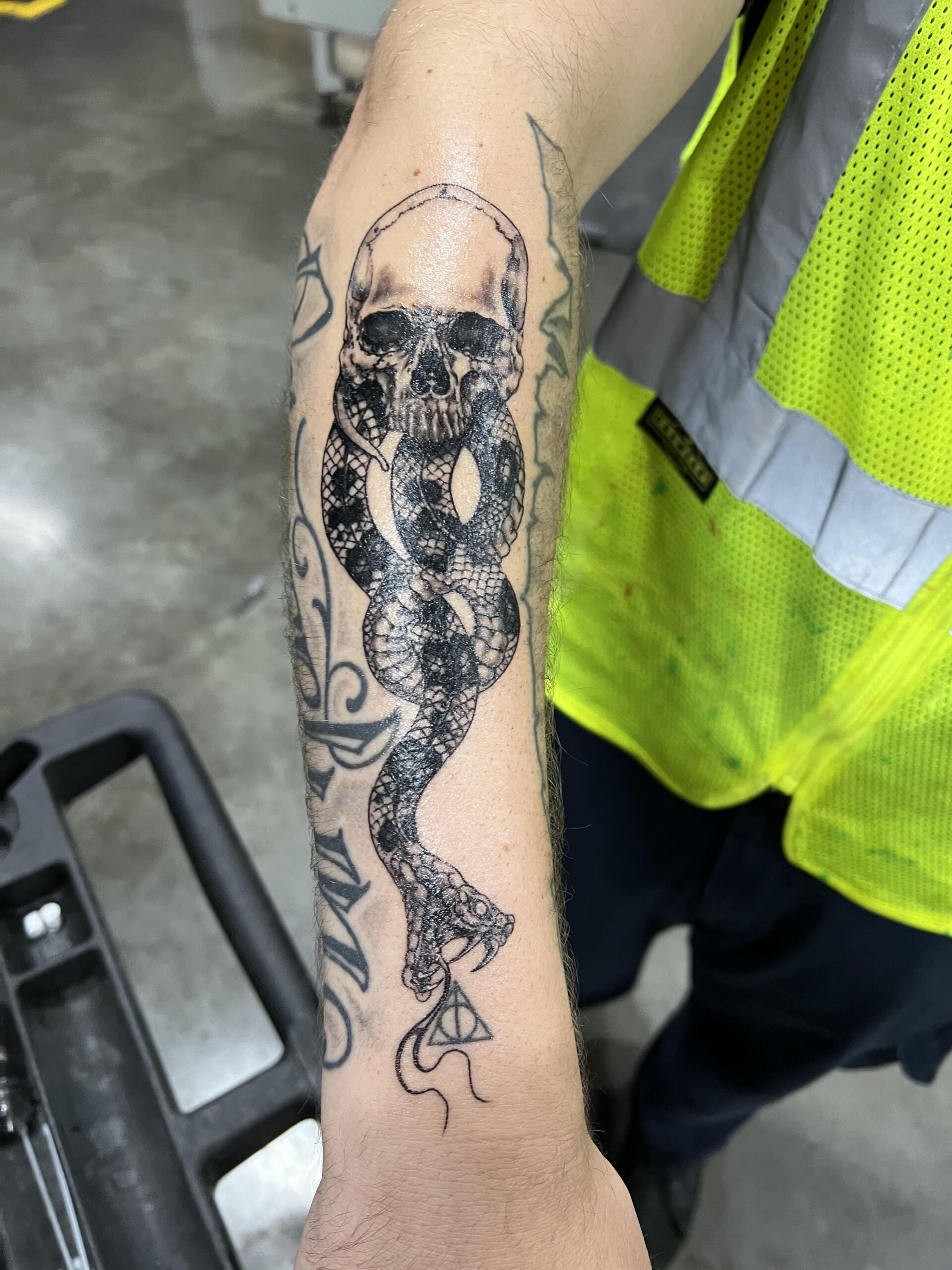 A man has a tattoo of a skull and snake on his arm