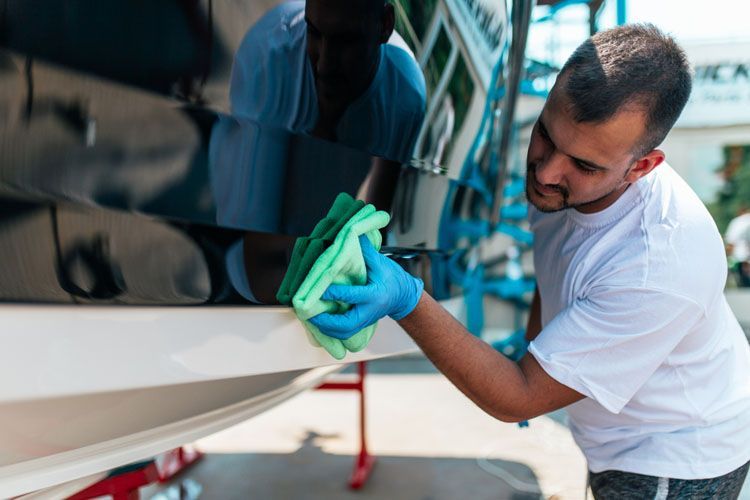 A Man is Cleaning a Boat With a Cloth and Gloves — V.I.P. Plastic Fabrication in Portsmith, QLD