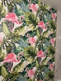 Wallpaper featuring a tropical pattern of bright pink flamingos nestled among large, layered green monstera leaves.