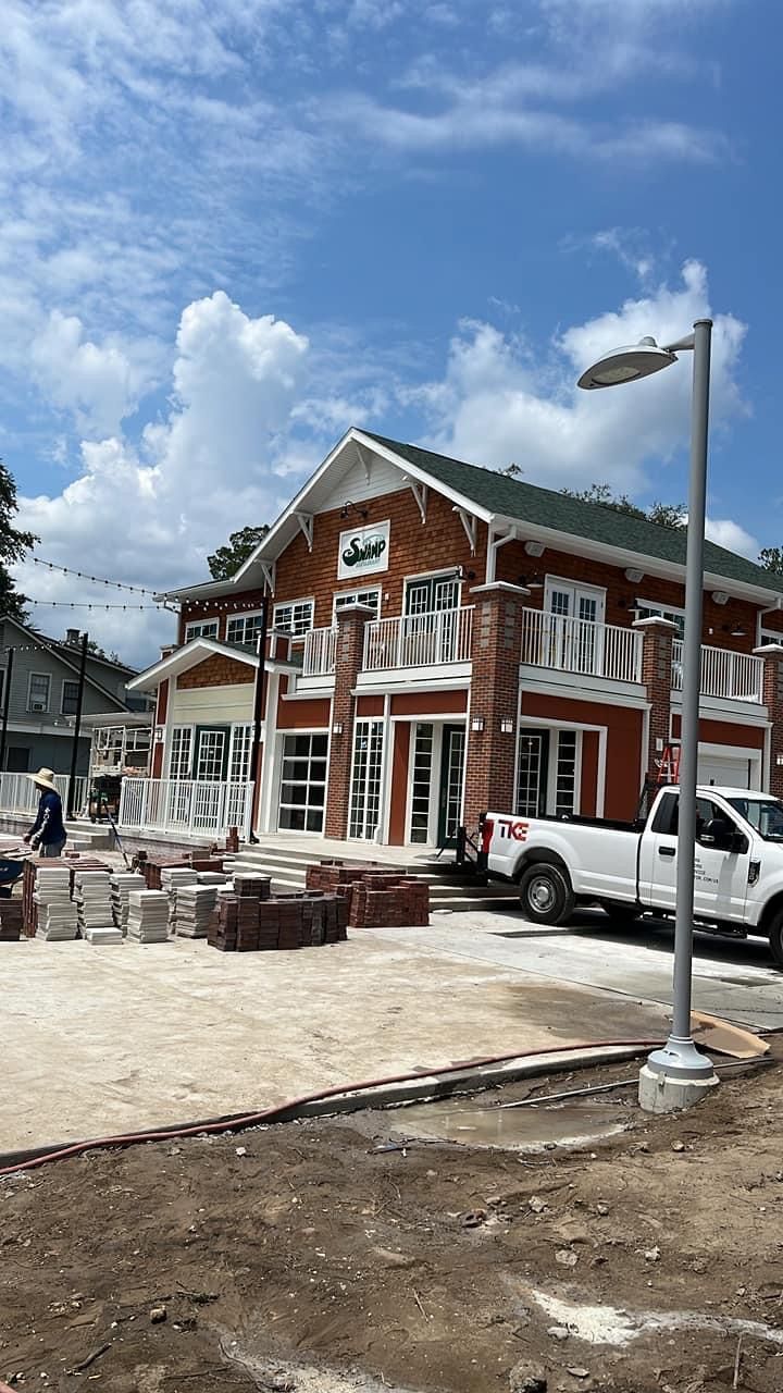 An orange building with brick accents under a blue sky, with a white truck parked in front and construction in progress.