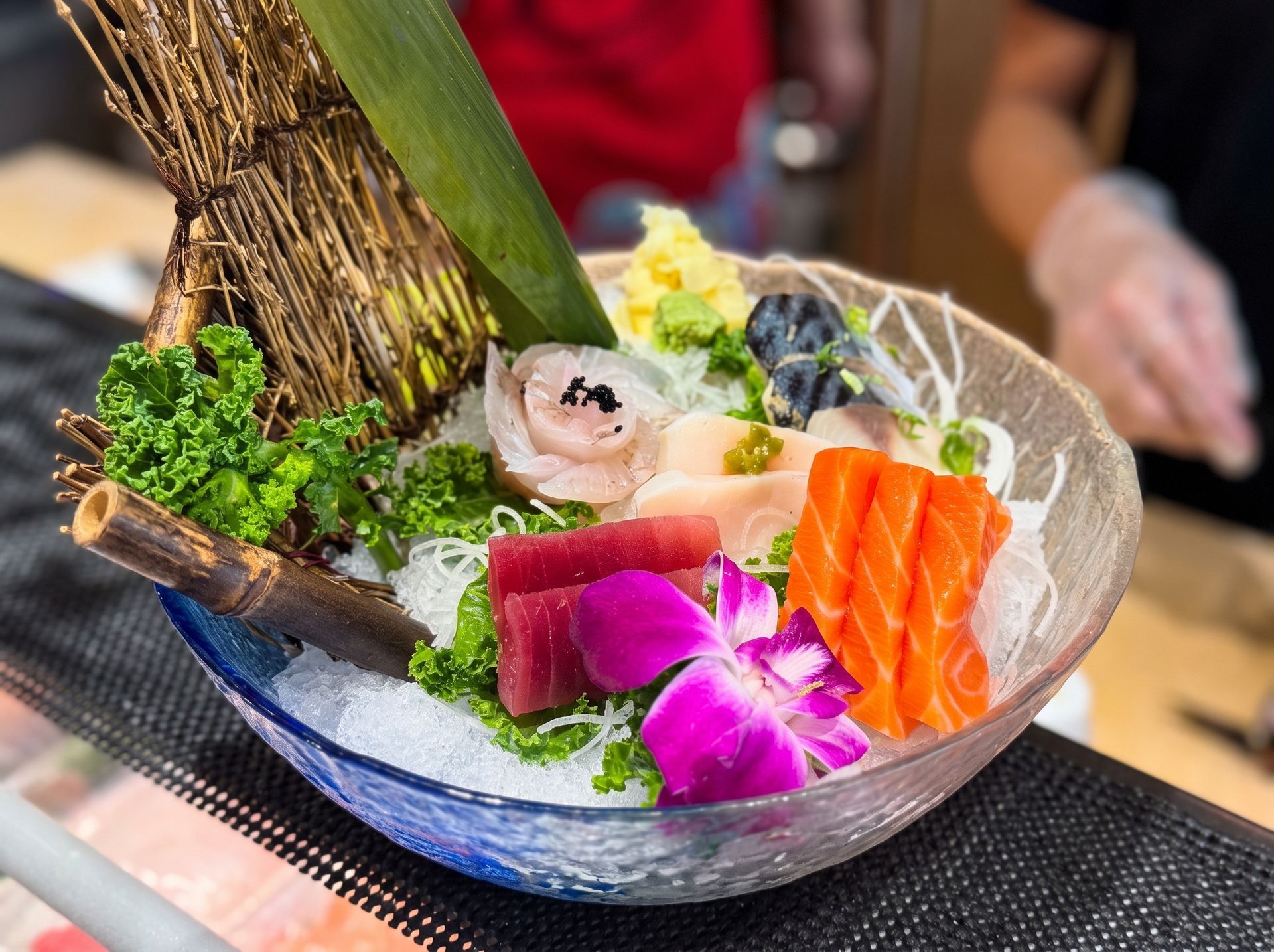 Assorted sashimi and garnishes in a glass bowl on a restaurant table