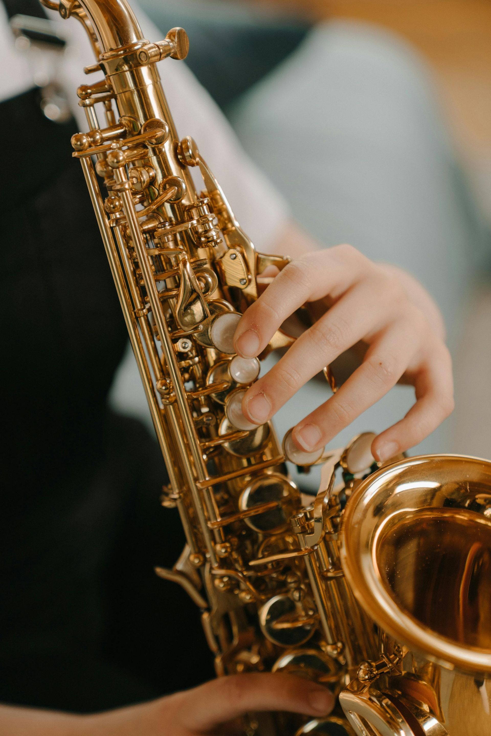A person playing a gold saxophone, their fingers pressing the keys on the instrument's body.