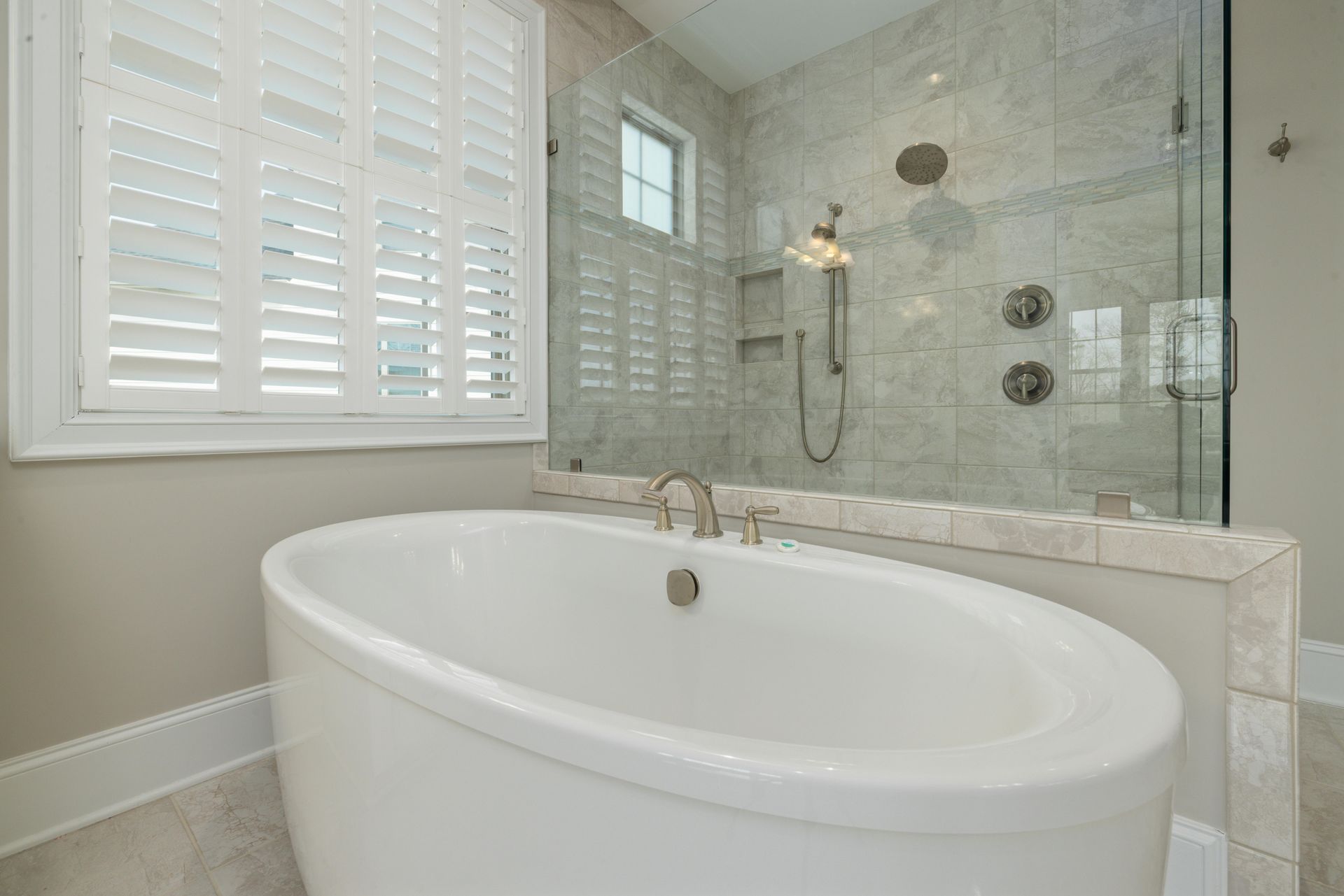 Large bathtub with separate shower area behind. White panel windows on the left.