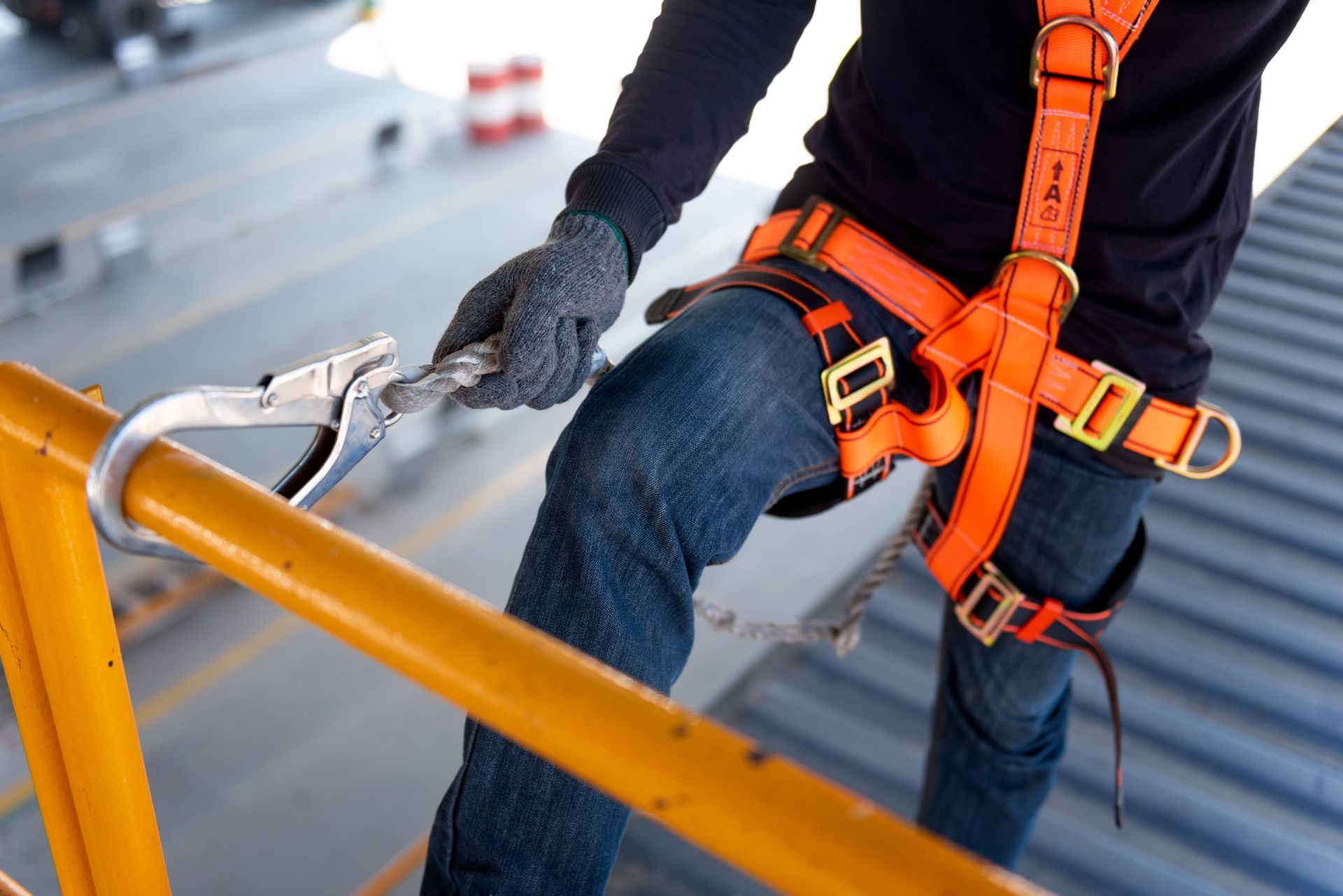 Ein Mann mit einem Sicherheitsgurt klettert ein Geländer hoch.