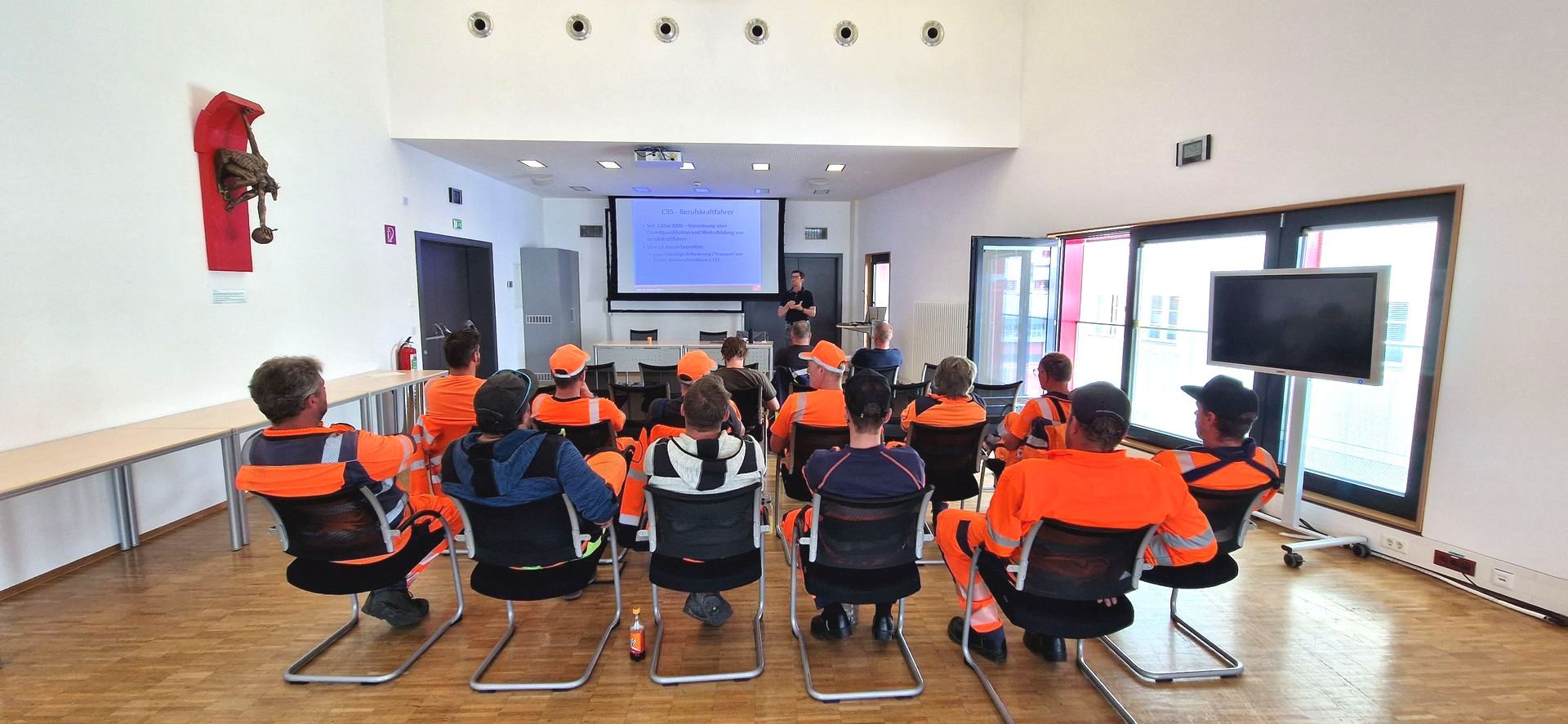 Eine Gruppe von Leuten sitzt in einem Raum und sieht sich eine Präsentation an.