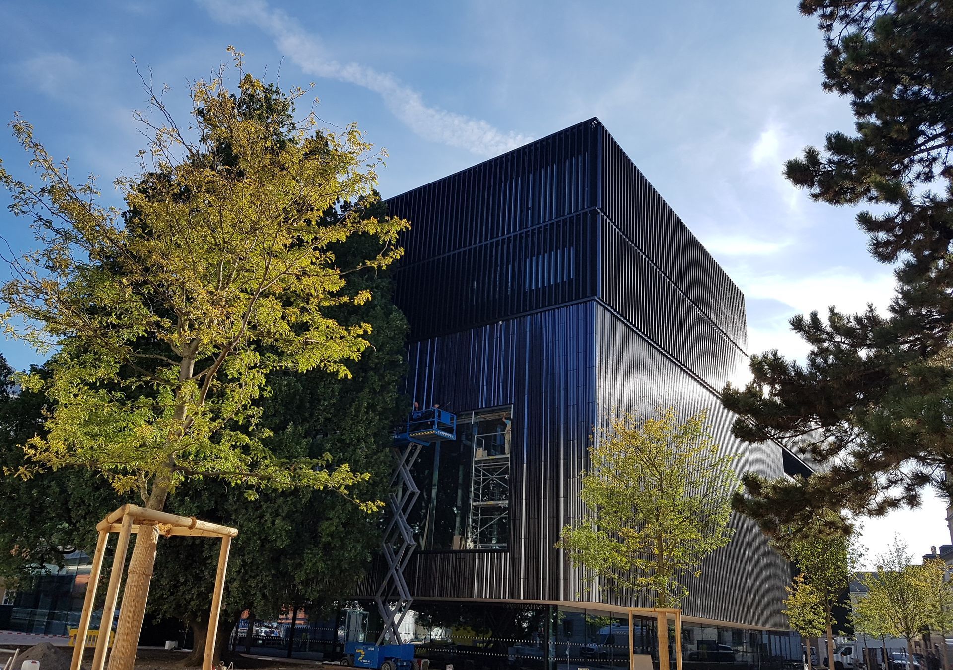 Ein großes Gebäude ist an einem sonnigen Tag von Bäumen umgeben