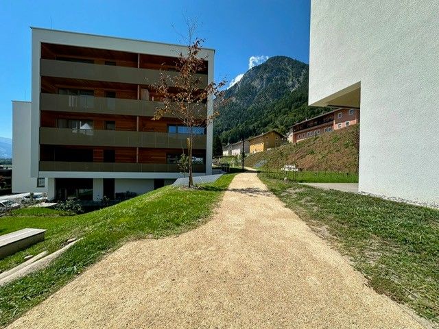 Ein großes weißes Gebäude mit Balkonen und Bergen im Hintergrund