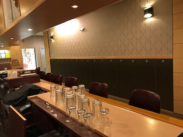 A row of empty glasses are sitting on a table in a restaurant.
