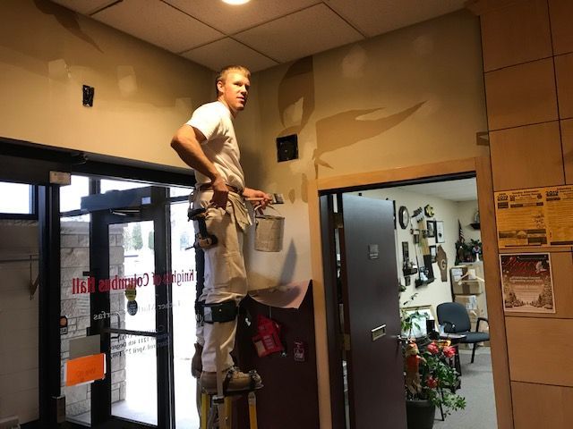 A man is standing on a ladder painting a wall