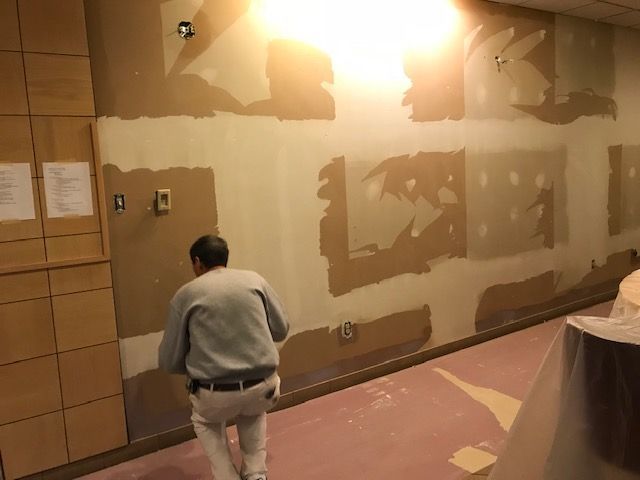 A man is standing in a hallway looking at a wall