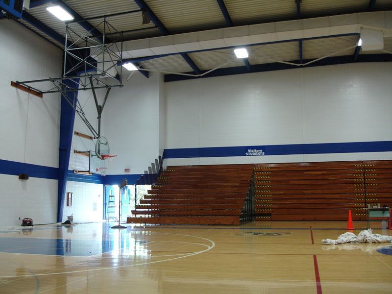 An empty gym with a basketball hoop and bleachers