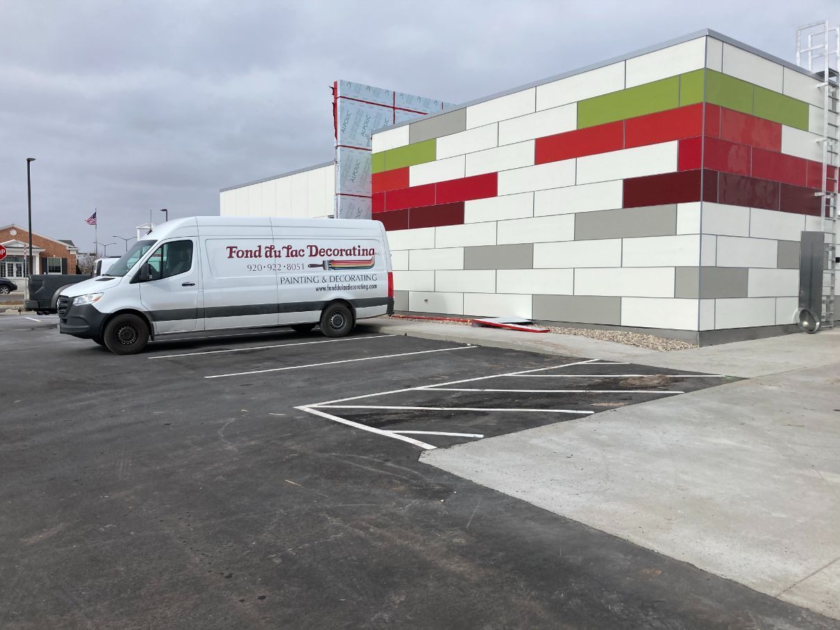A white van is parked in front of a building under construction.