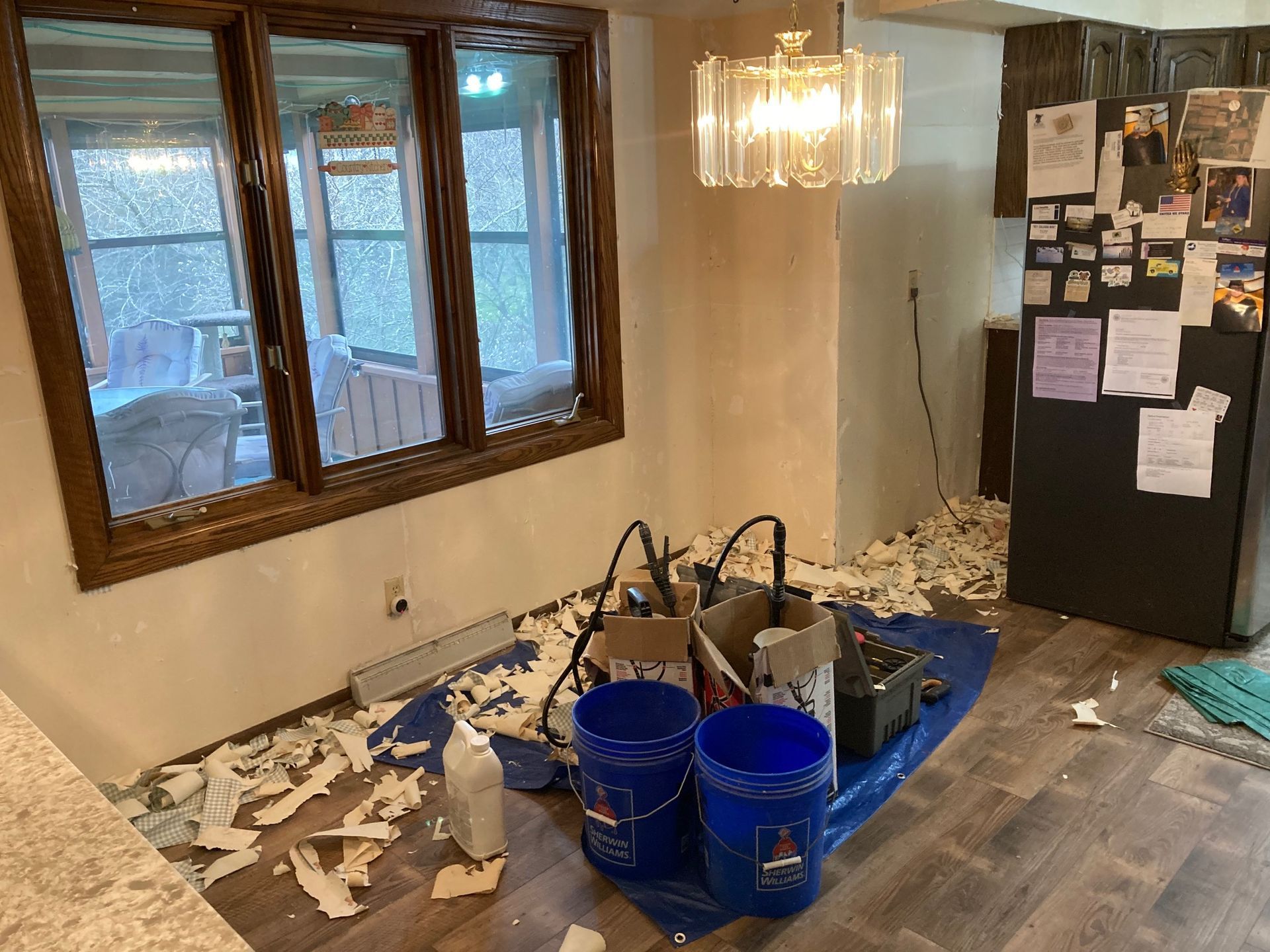 A messy room with buckets and boxes on the floor.