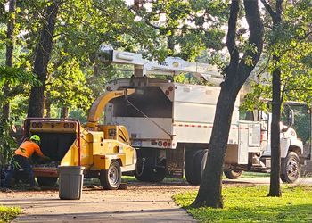 A man is working on a tree chipper next to a truck.