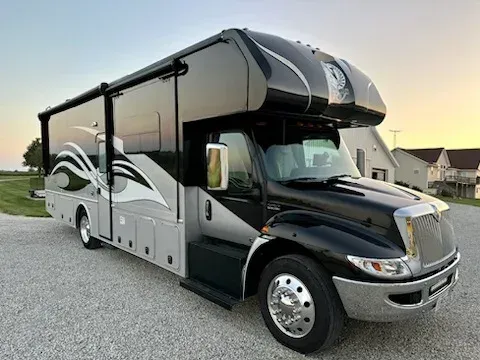Black and white luxury motorhome parked on a gravel road at sunset