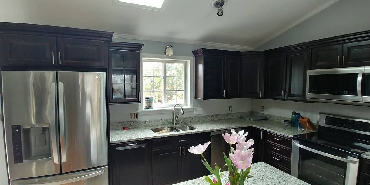 Bright modern kitchen with stainless steel appliances, dark cabinets, and a window over the sink