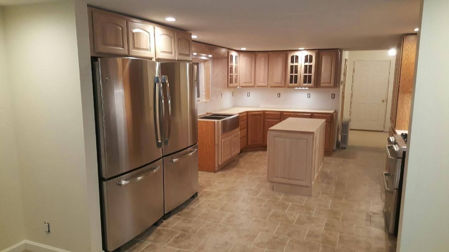 Modern kitchen with stainless steel appliances, light wood cabinets, tiled floor, and central island