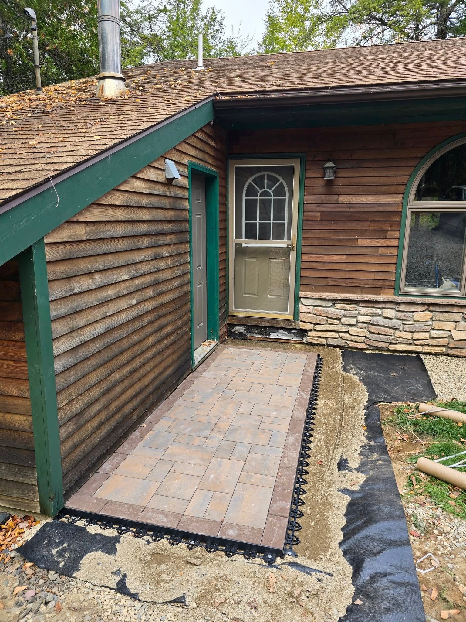 Wooden ramp leading to a house entrance with green trim and a tan screen door.