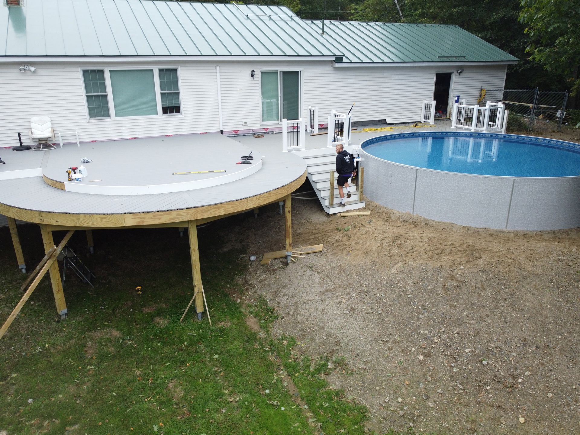 Backyard with above-ground pool, hot tub deck, and house with green roof