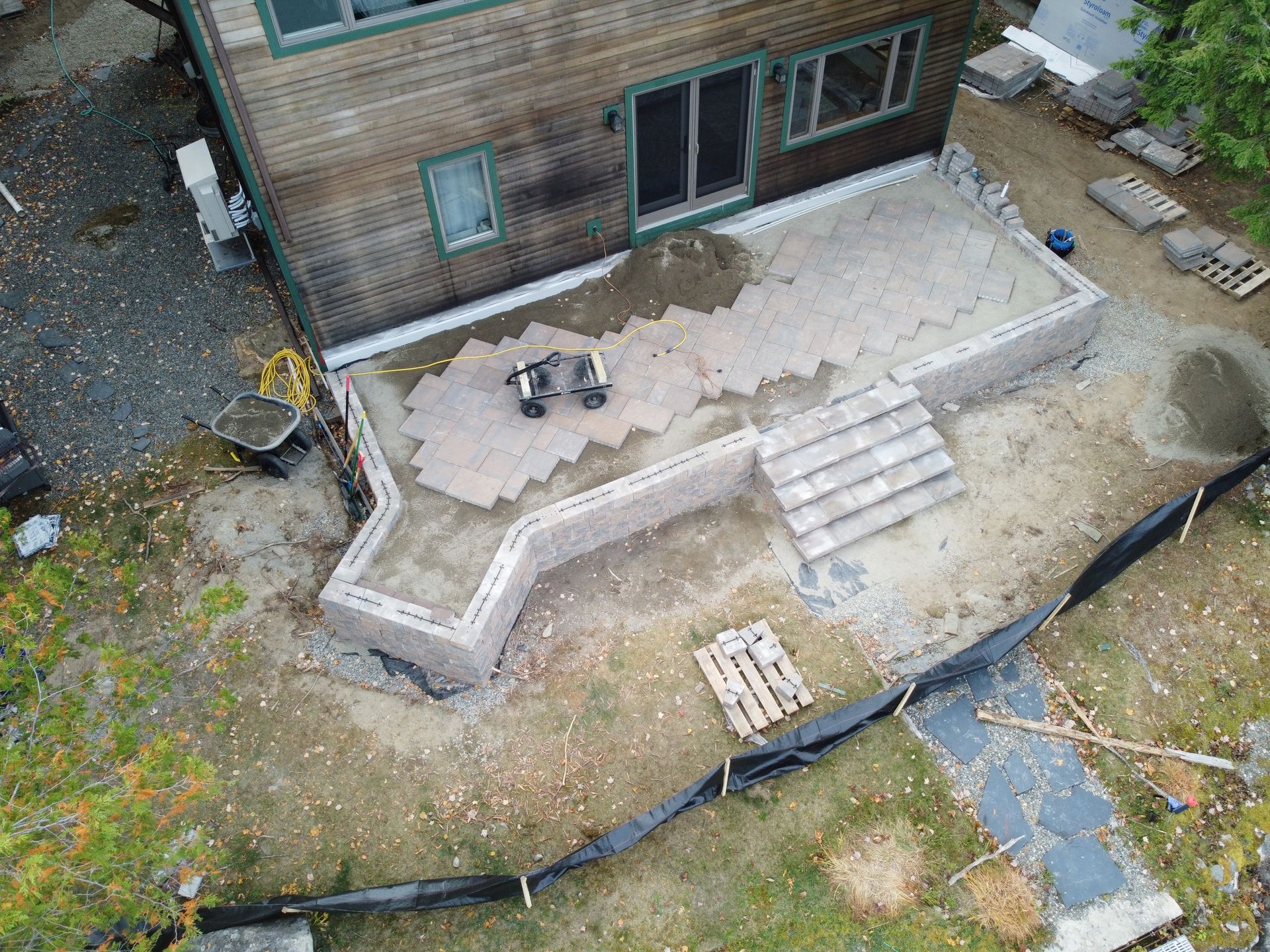 Backyard patio with stairs, a small grill, and a house deck under construction