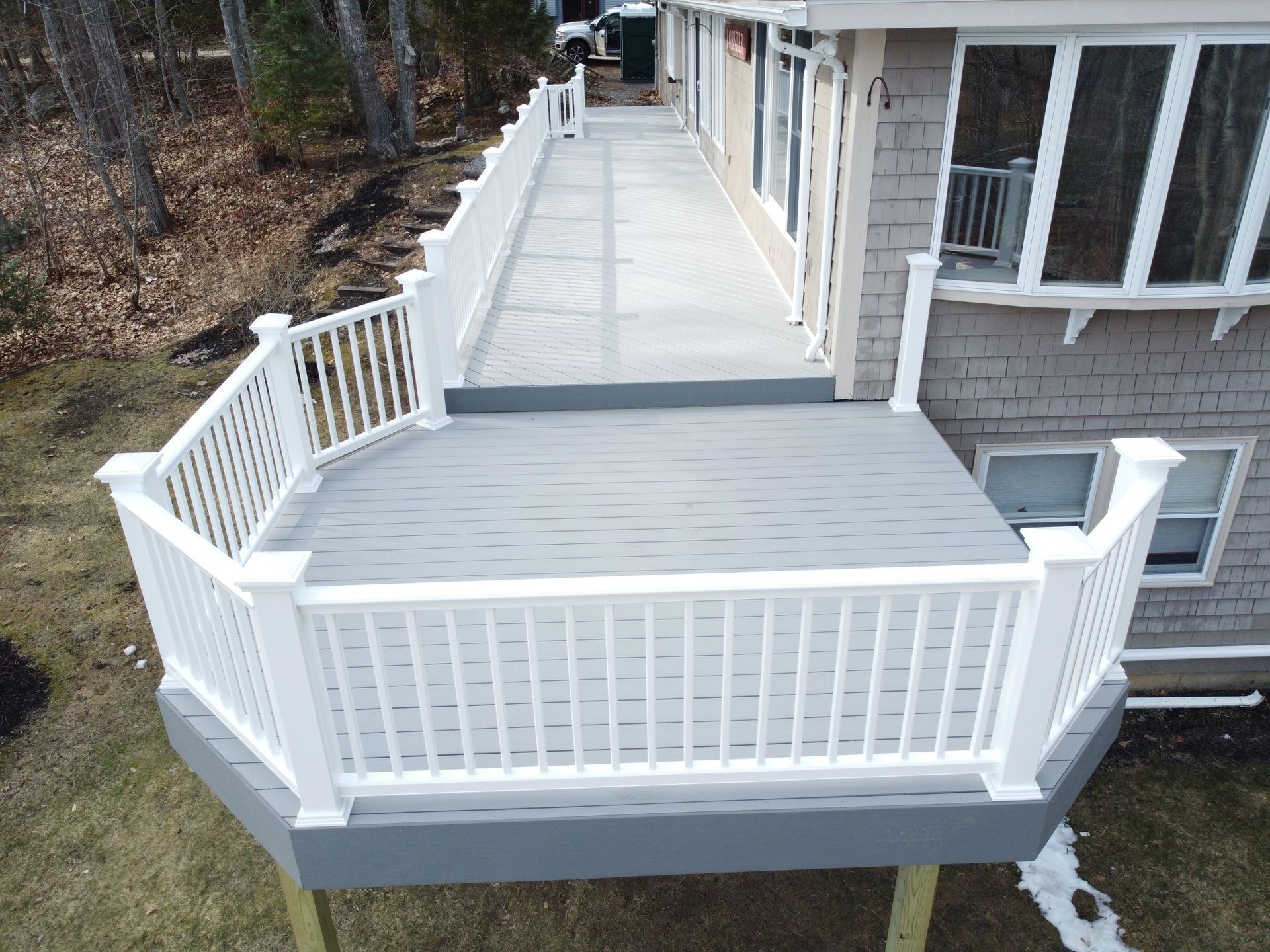 White accessible deck and ramp attached to a house, with railings and a concrete walkway.