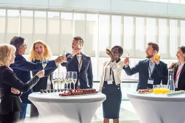 People at an event, toasting with champagne and other drinks.