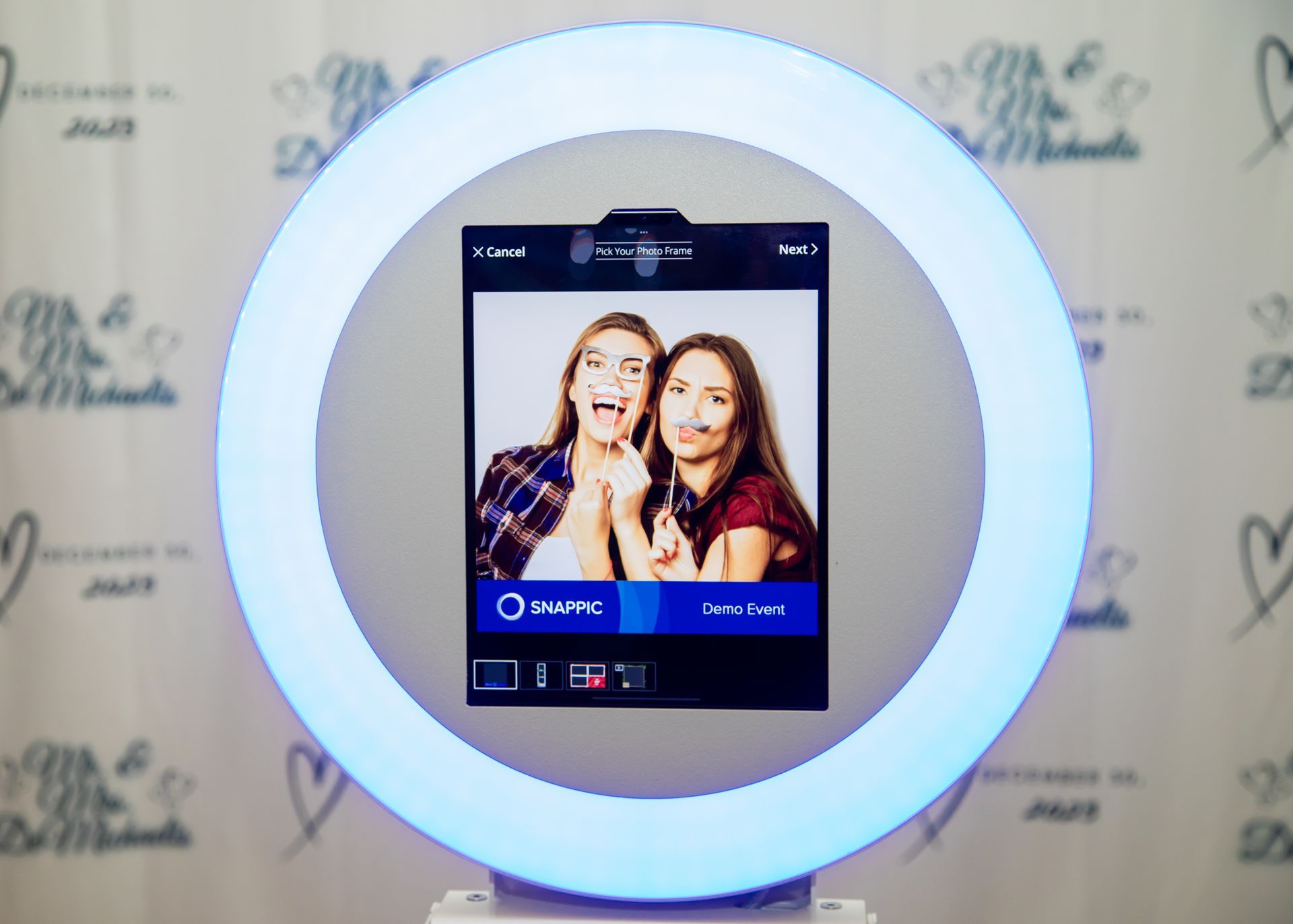Photo booth with two women posing inside a glowing circular light frame.