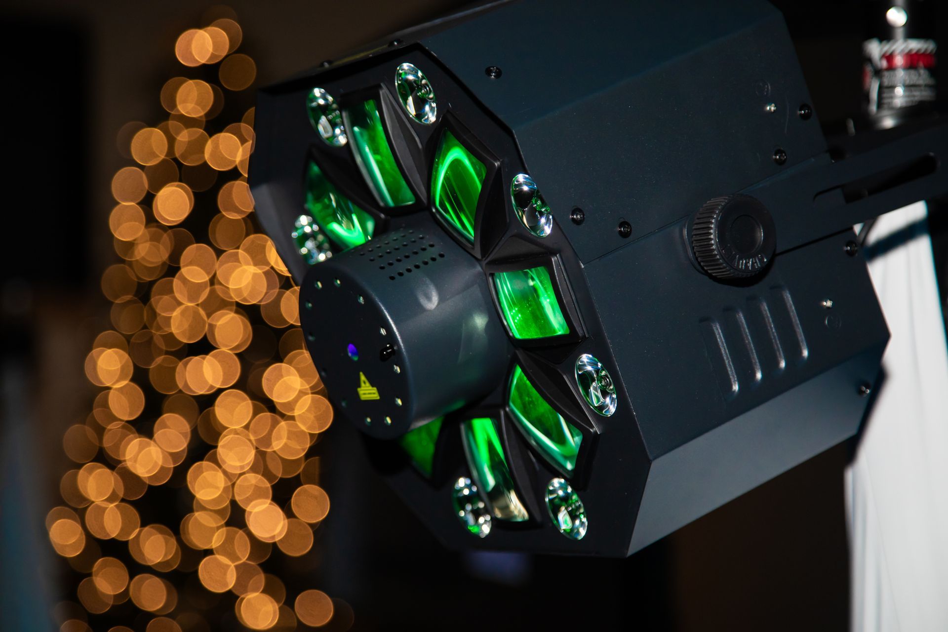 Black and green stage light with an octagonal shape, directed towards a blurred background of yellow lights.