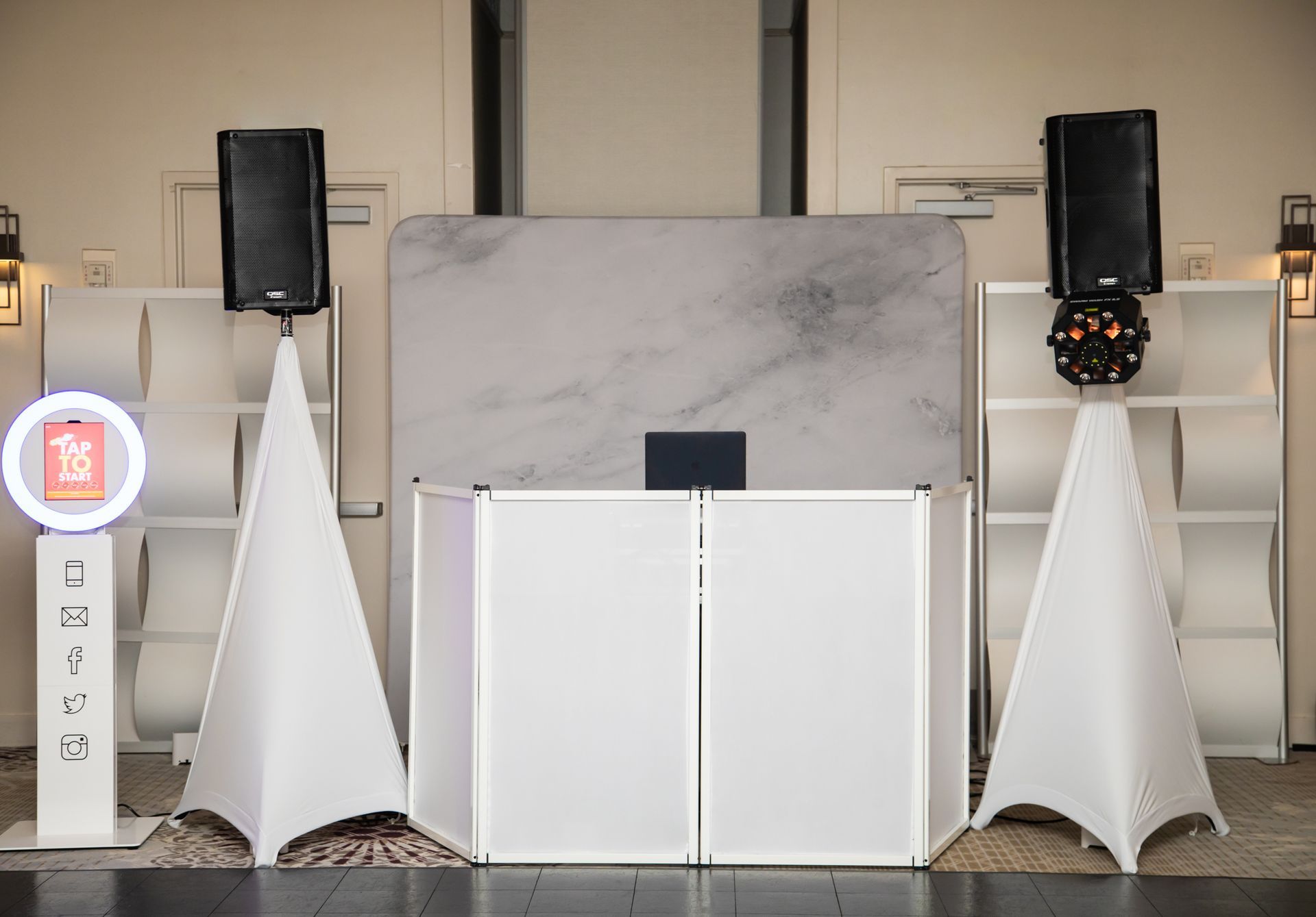 DJ setup with speakers, photo booth, and marble backdrop. White and black color scheme.