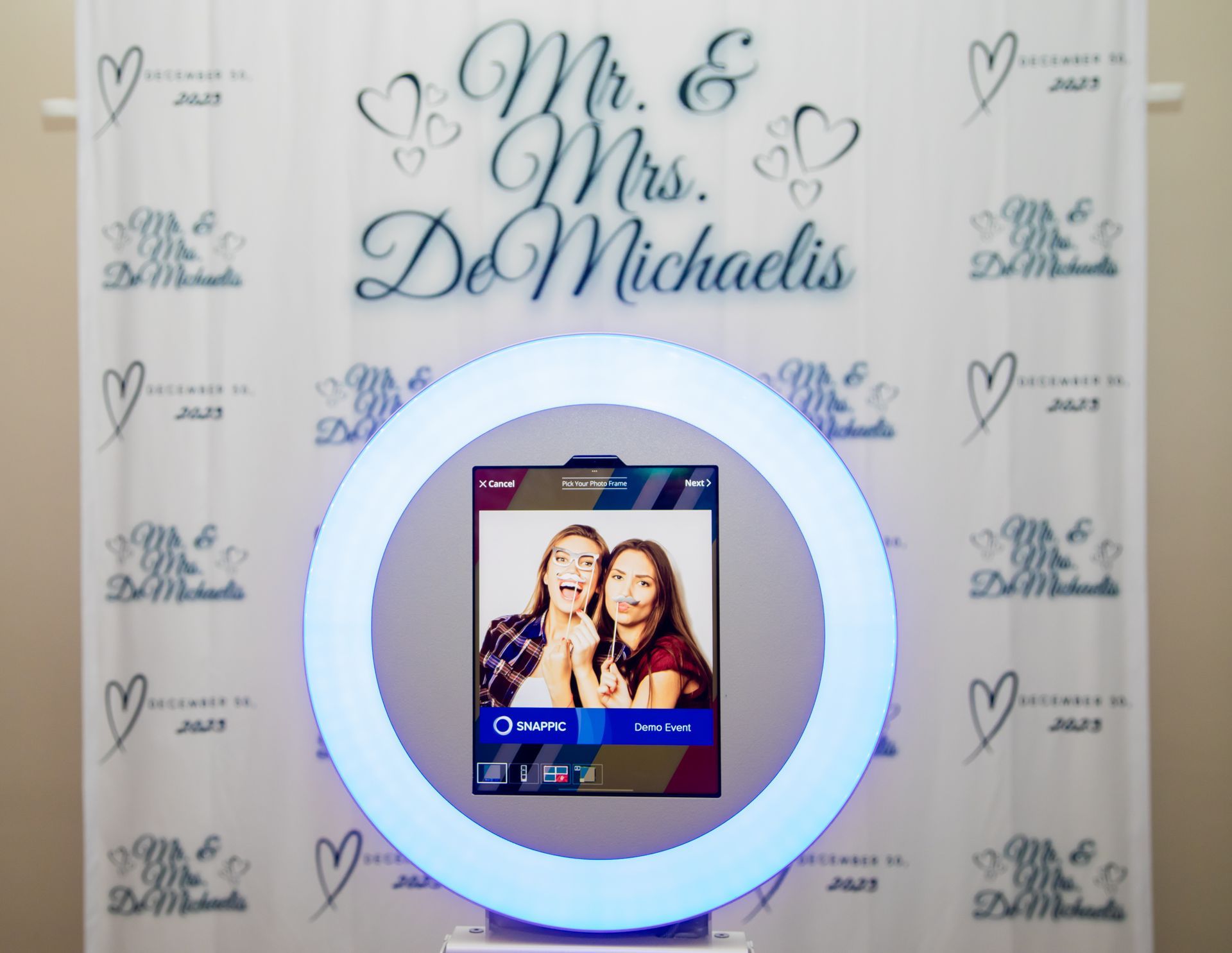 Photo booth at a wedding with two people posing. Backdrop says