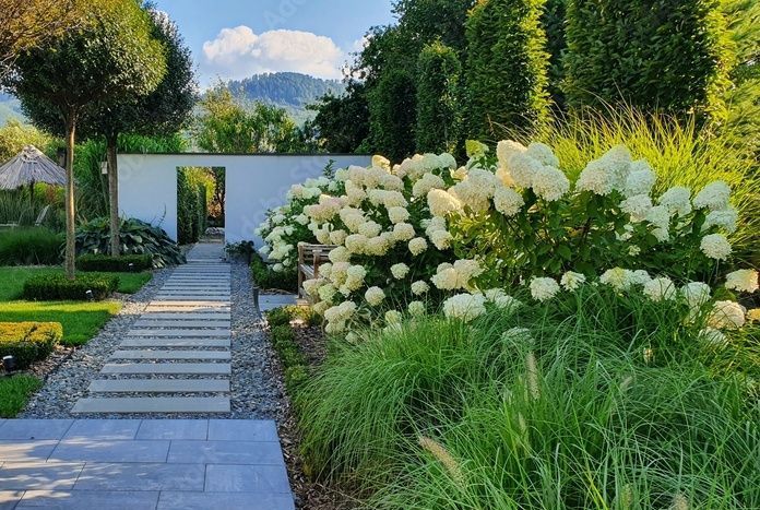 Ein Weg, der zu einem von Blumen und Gras umgebenen Haus führt.