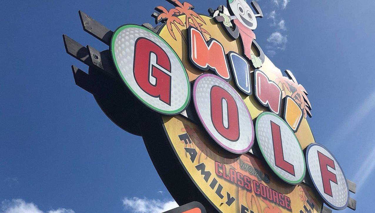 A colorful, angled sign against a blue sky advertises 