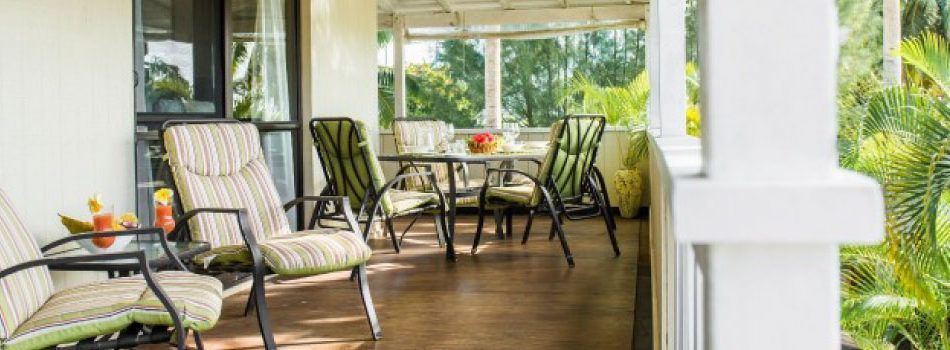 A patio with outdoor dining furniture and lounge chairs overlooking a lush, green tropical garden.