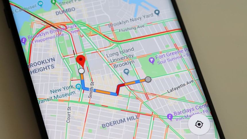 A close-up of a smartphone screen displaying a Google Maps route through Brooklyn, showing traffic congestion levels.
