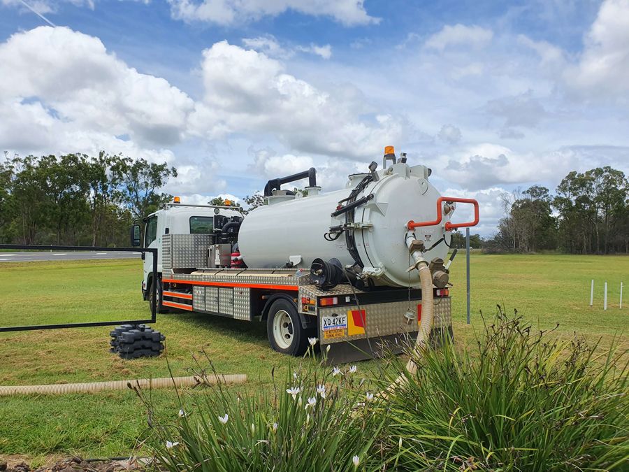 A vacuum truck is parked in a grassy field.