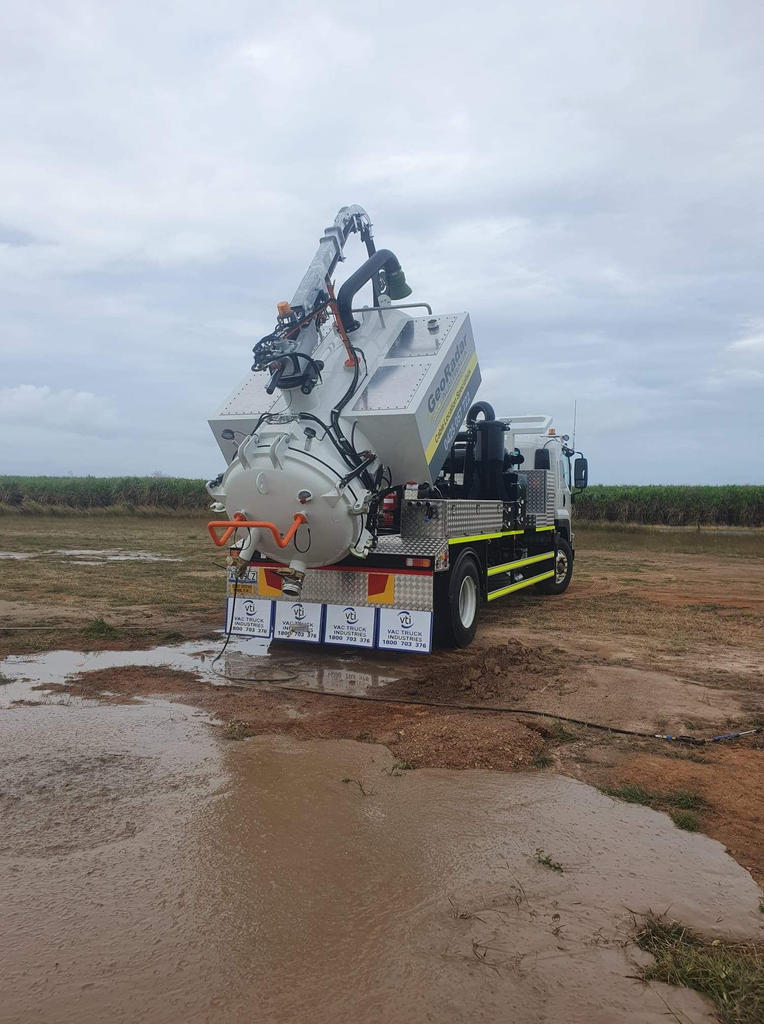A vacuum truck is parked in a muddy field.