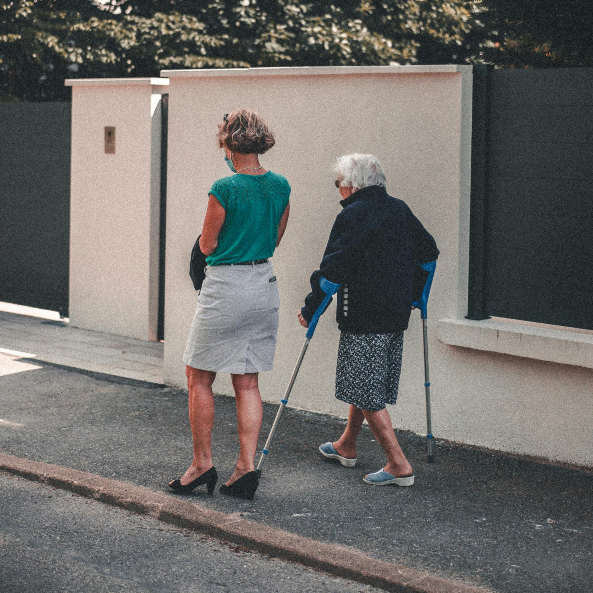 An elderly man with a cane is sitting on a couch with a nurse.