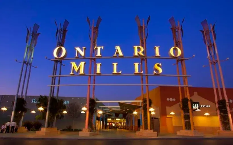 Ontario Mills shopping center entrance at dusk with illuminated sign and palm trees