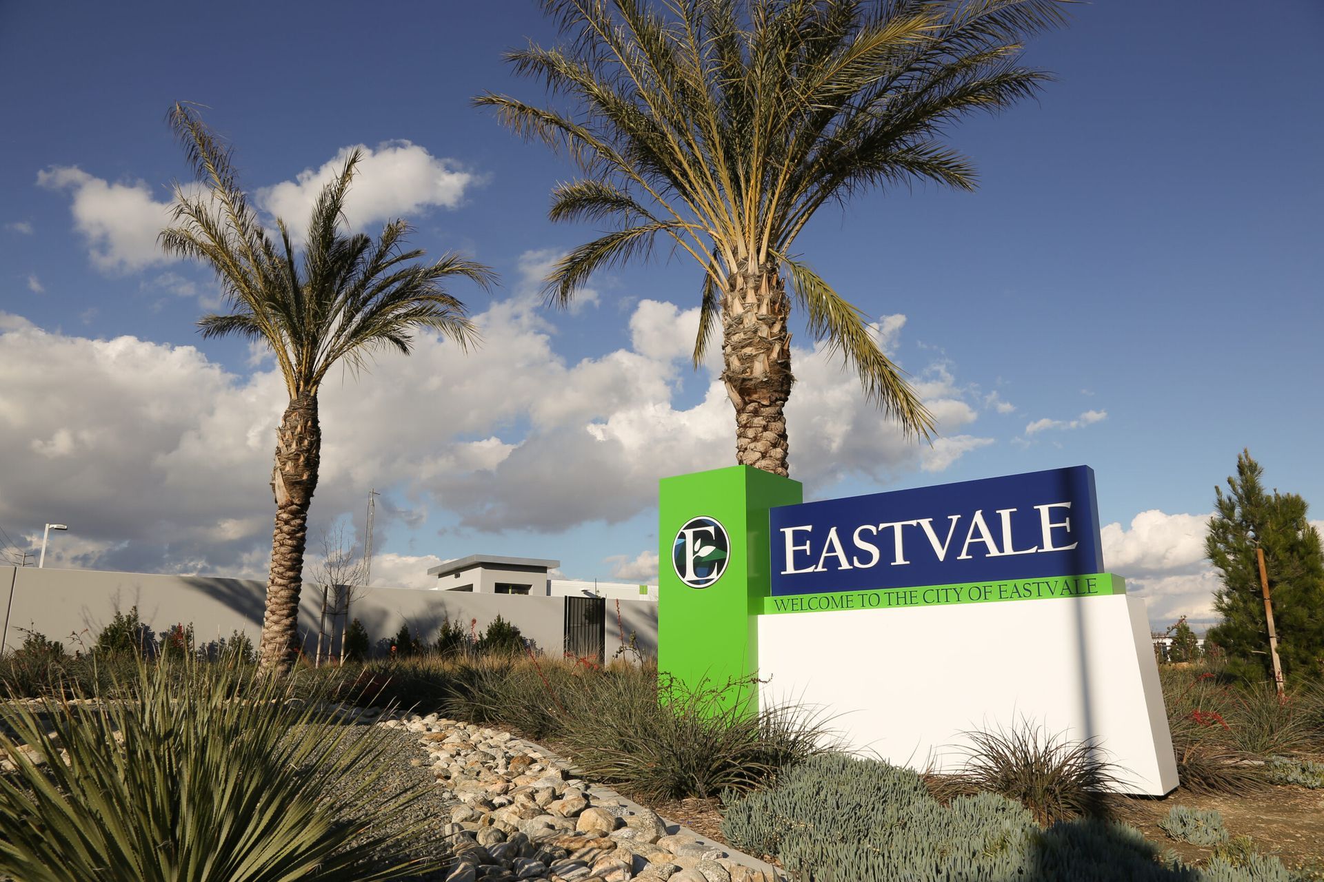 Eastvale city sign beside palm trees and desert landscaping under a blue sky