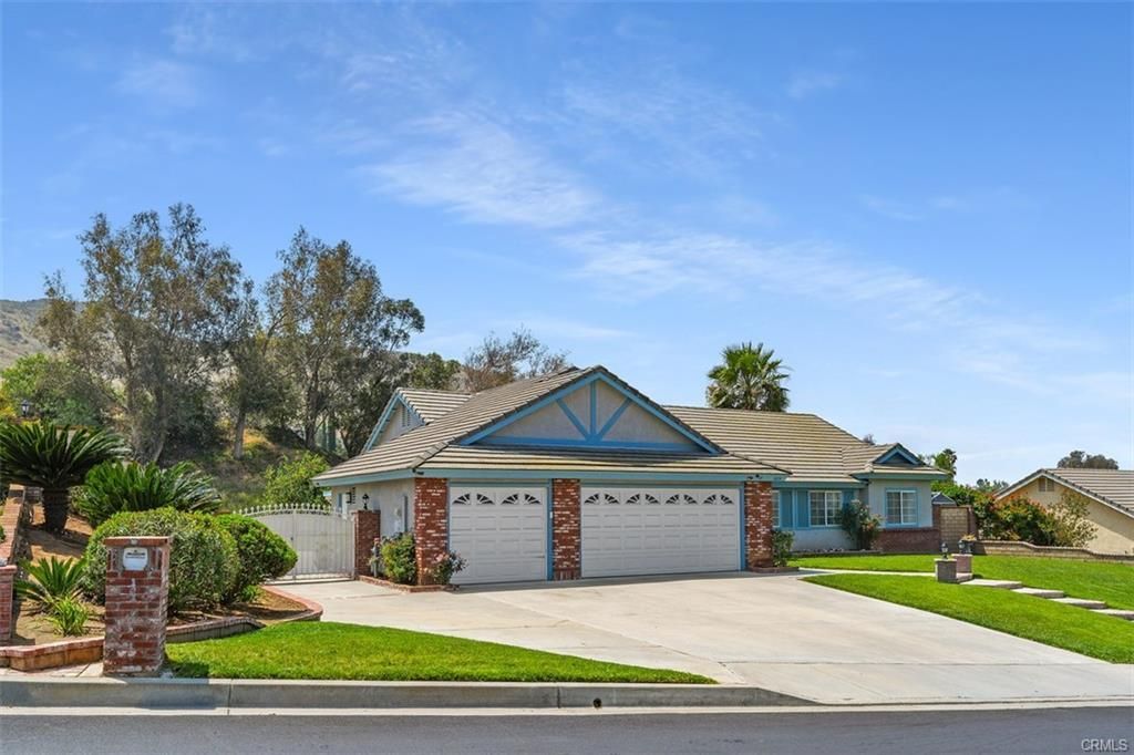 Single-story suburban house with two white garage doors, manicured lawn, and clear blue sky