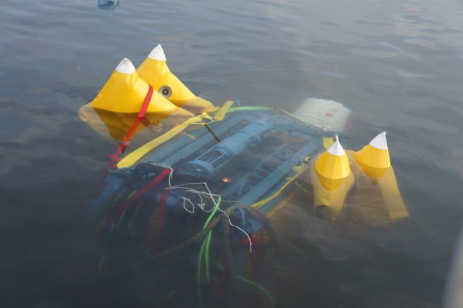 A boat with yellow buoys attached to it is floating in the water