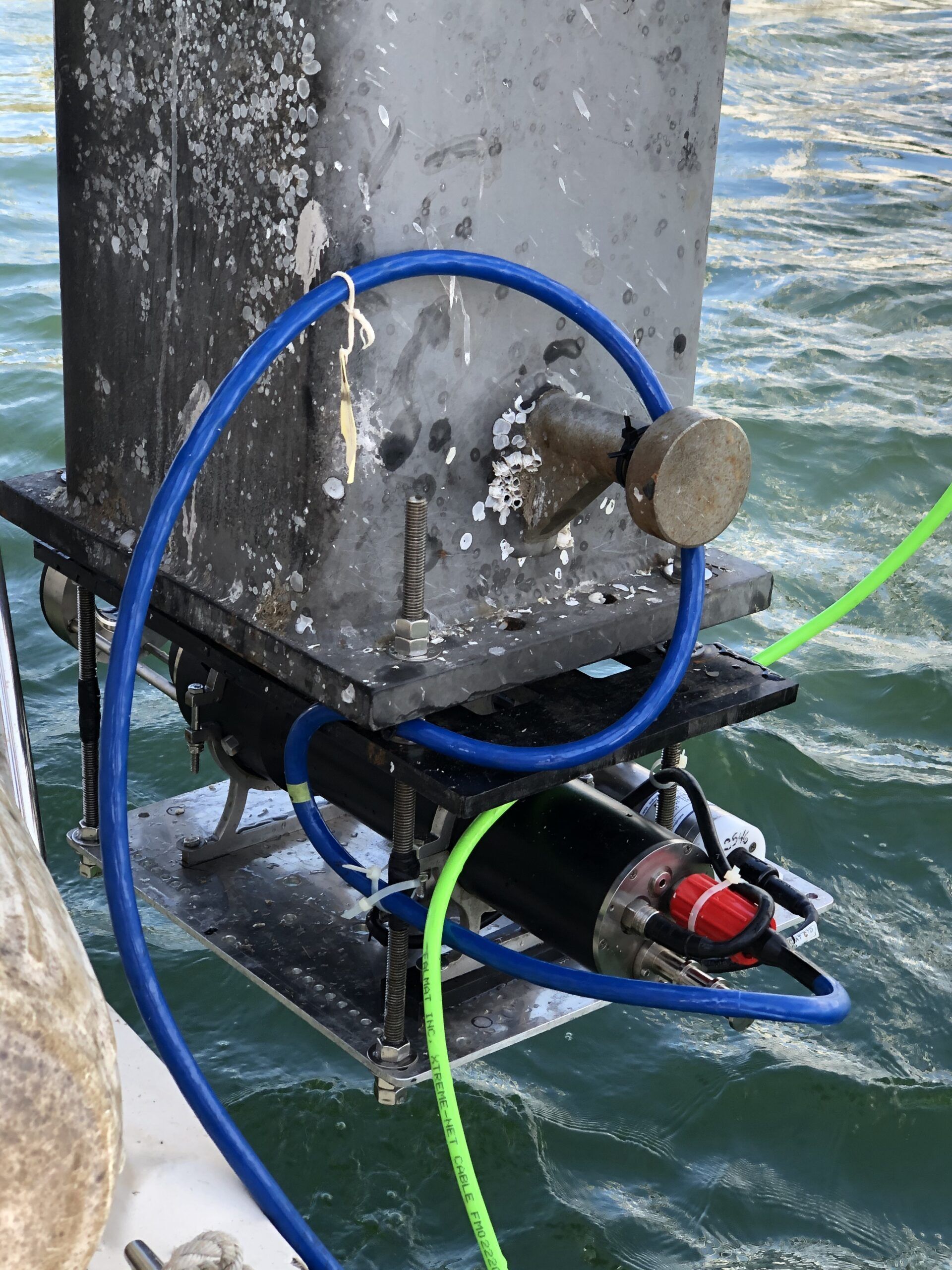 A blue and green hose is attached to a metal object in the water