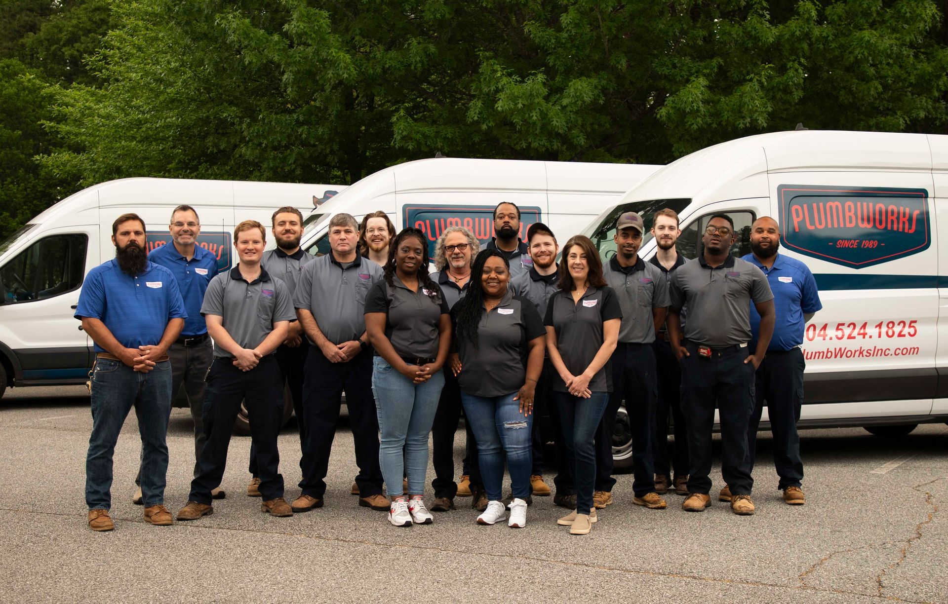 Plumb Works Career Plumbworks team stands together, holding sign in front of building.