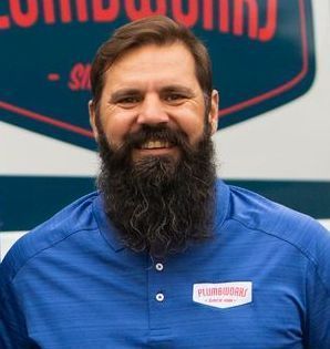 Man with a full beard wearing a blue polo shirt smiles, logo 
