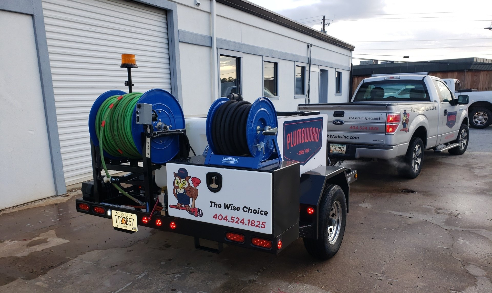 Truck towing a trailer with water hoses and tanks. The trailer has a logo that reads