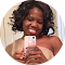 Woman taking selfie, smiling, holding phone, in bathroom, neutral skin tone.