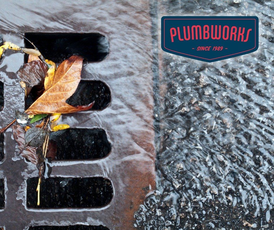 Water flowing over a sewer grate with leaves;